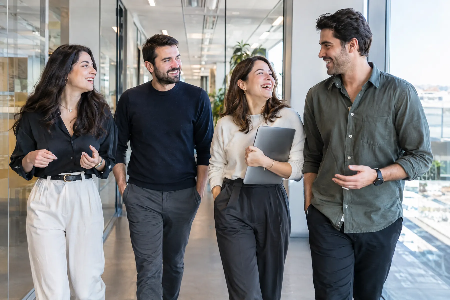Ofis koridorunda sohbet ederek yürüyen dört çalışma arkadaşı